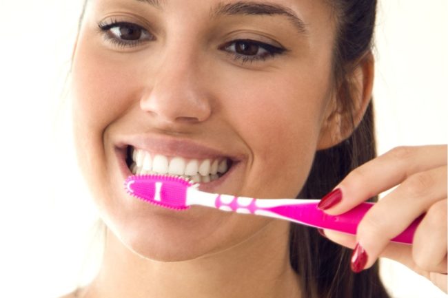mujer que goza de una boca sana se cepilla los dientes