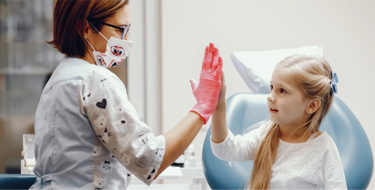 niña contenta en el dentista chocando los cinco con su odontopediatra