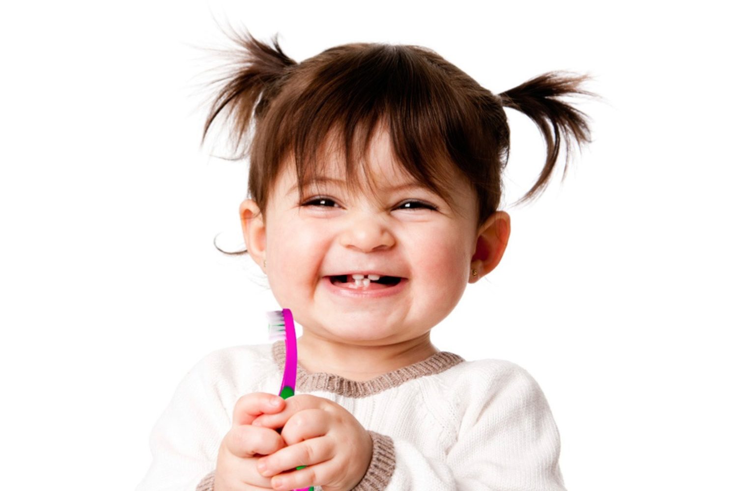 niña pequeña sonríe sujetando un cepillo de dientes