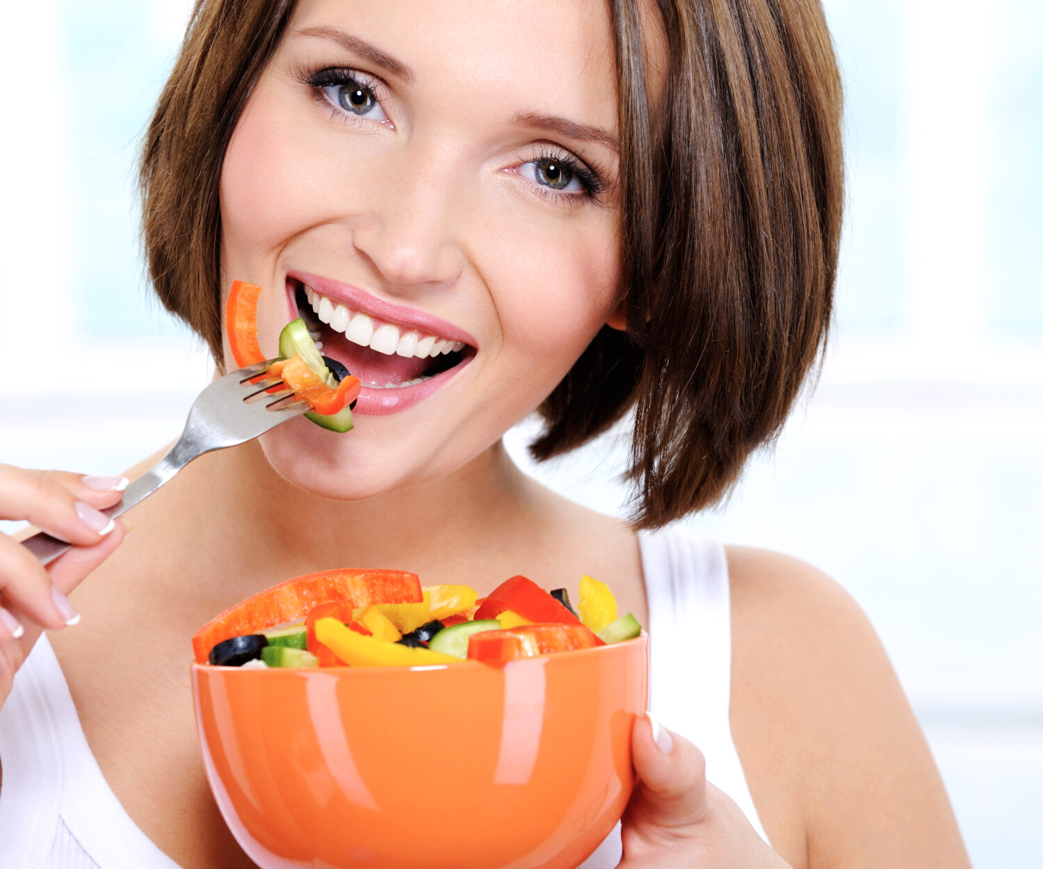 Portrait of a beautiful caucasian smiling young woman eats vegetable salad